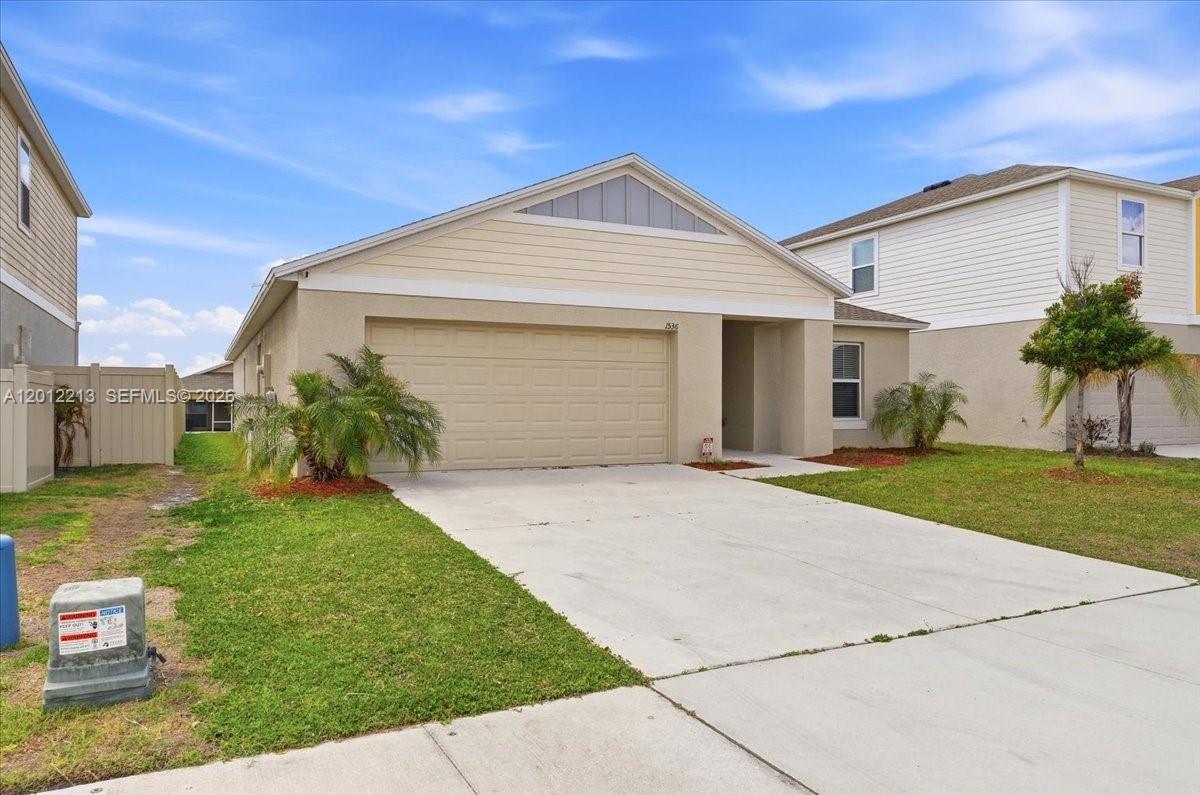 A single-story house with a beige stucco exterior, a two-car garage, and a concrete driveway — 1536 Axel Circle, Winter Haven FL 33880, WINTER HAVEN, FL