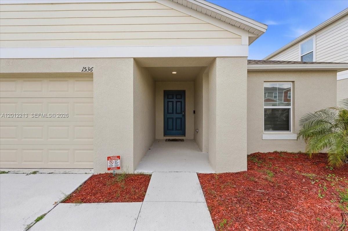 The exterior of a single-story house features a garage, a covered entryway, and red mulch — 1536 Axel Circle, Winter Haven FL 33880, WINTER HAVEN, FL