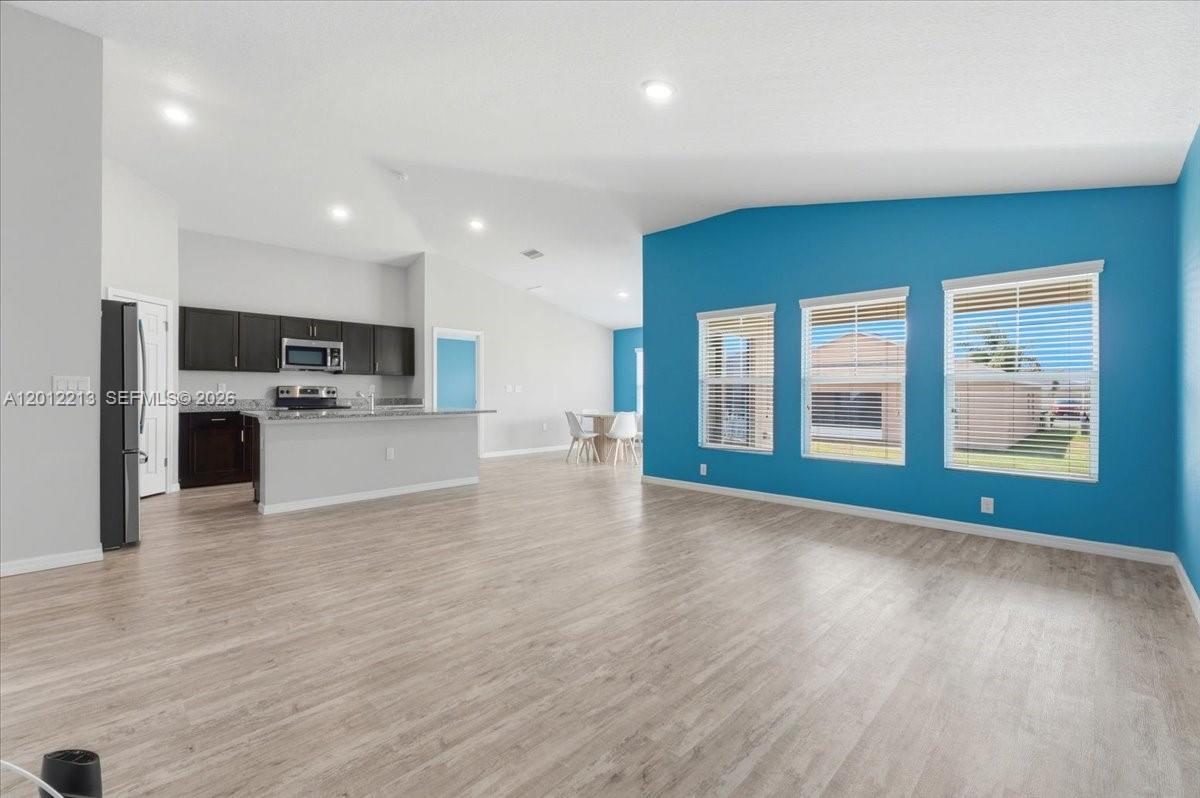 An open-concept living area features light wood flooring, a blue accent wall, and a kitchen — 1536 Axel Circle, Winter Haven FL 33880, WINTER HAVEN, FL