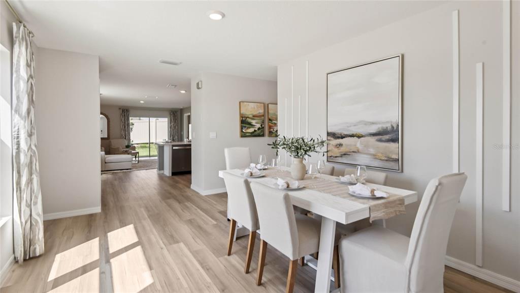 A dining room features a white table with six chairs and wall molding accents — 3070 EVENMORE WAY, WILDWOOD, FL