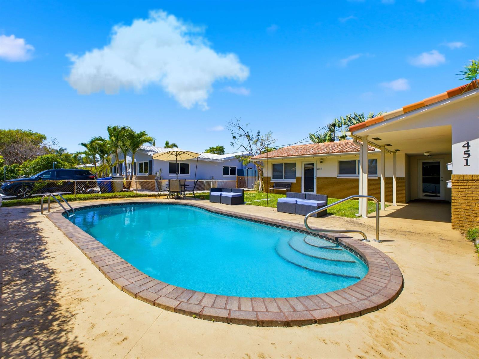 A swimming pool sits in the backyard of a single-story house with outdoor seating — 451 SE 1st Avenue # B, Pompano Beach FL 33060, POMPANO BEACH, FL