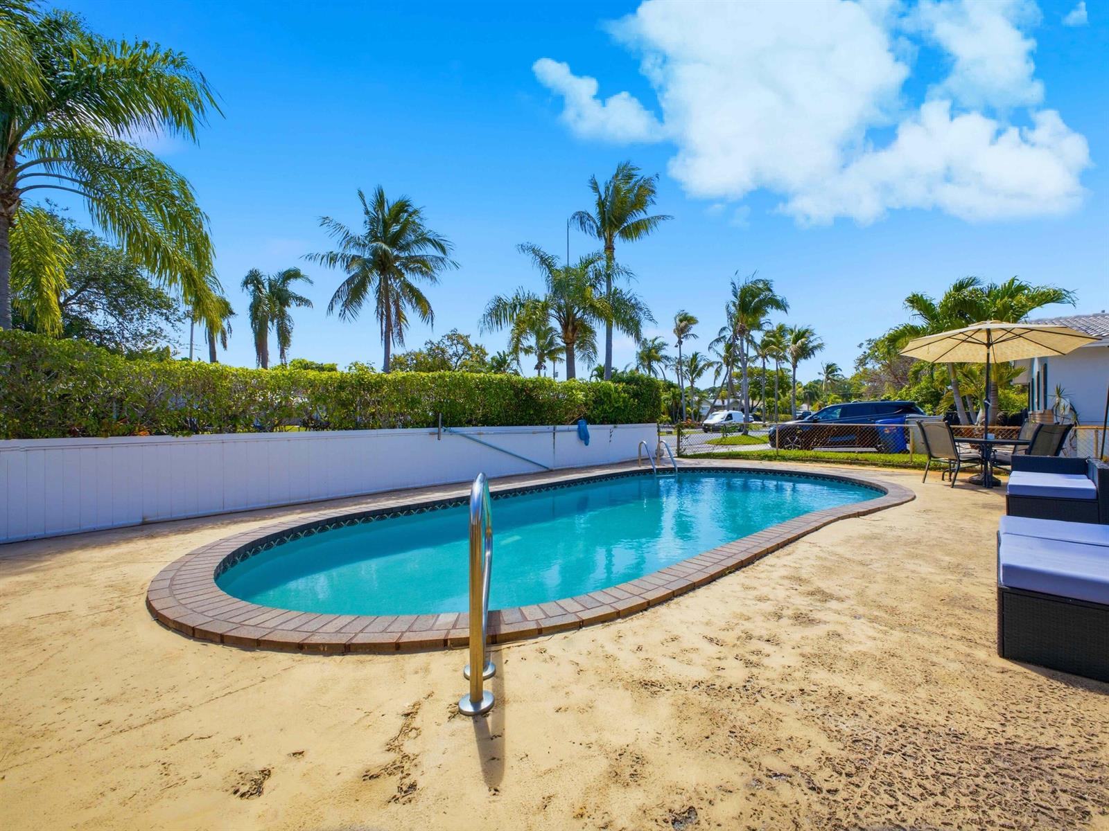 An oval swimming pool with a brick border sits on a patio with palm trees — 451 SE 1st Avenue # B, Pompano Beach FL 33060, POMPANO BEACH, FL