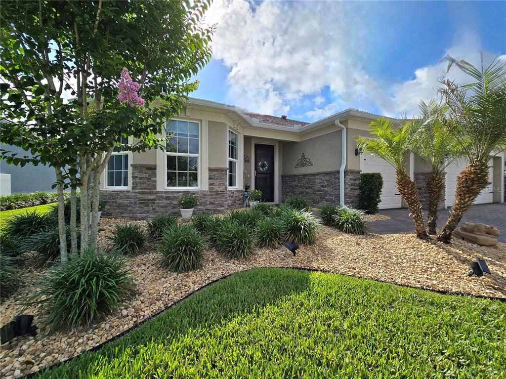 A single-story house features a stone facade, a front porch, and a landscaped rock garden — 2743 RIVER CREEK LANE, ST CLOUD, FL