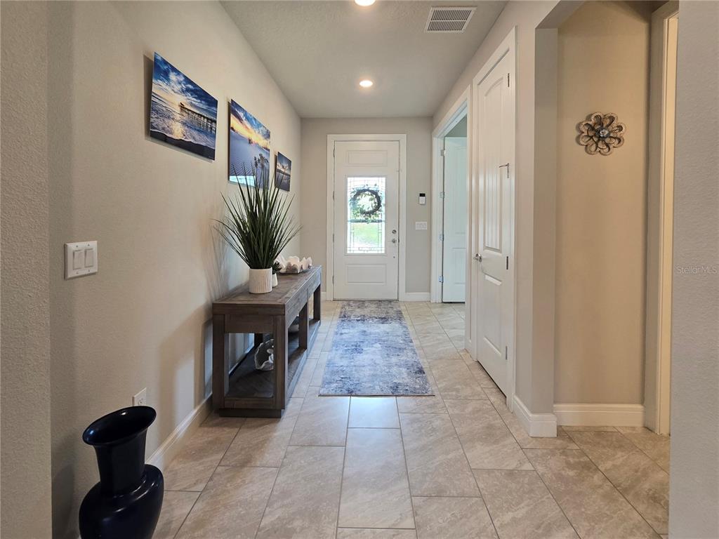 A tiled entryway features a wooden console table, wall art, and a front door — 2743 RIVER CREEK LANE, ST CLOUD, FL