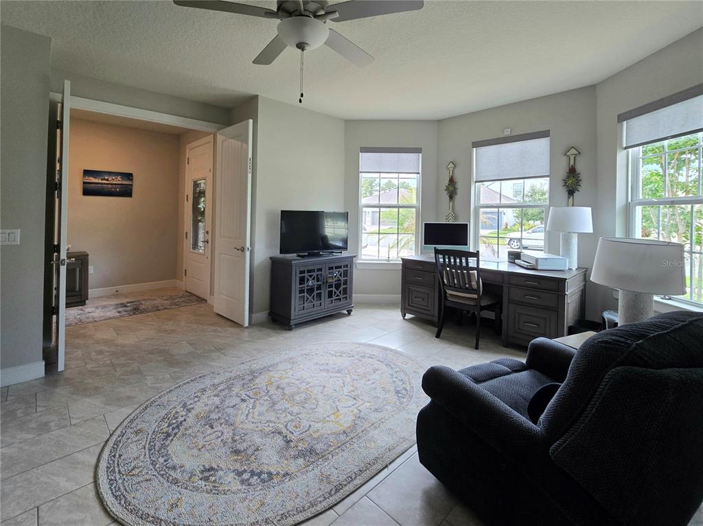A home office with tile flooring, a desk, a television, and a rug — 2743 RIVER CREEK LANE, ST CLOUD, FL