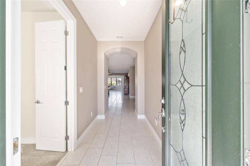 A view from a front doorway looking down a tiled hallway toward an open living area — 9601 SW 65TH PLACE, OCALA, FL