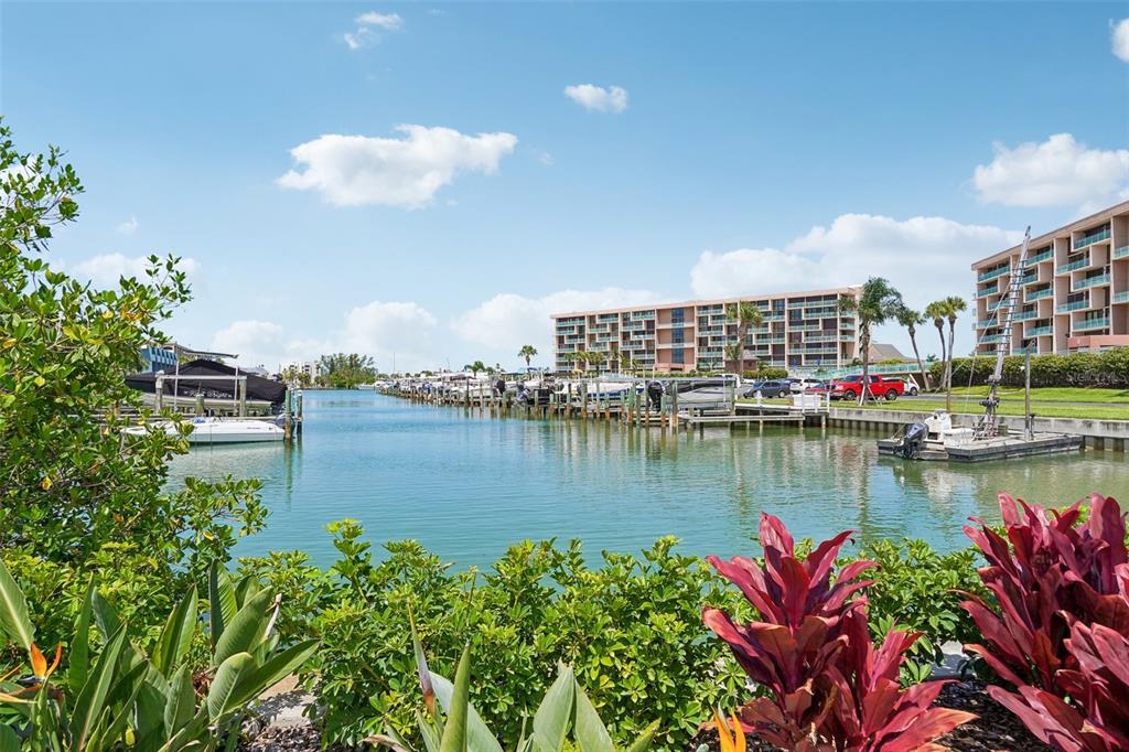 A marina with numerous docked boats sits in front of multi-story residential buildings — 1 KEY CAPRI UNIT 406W, ST PETERSBURG, FL