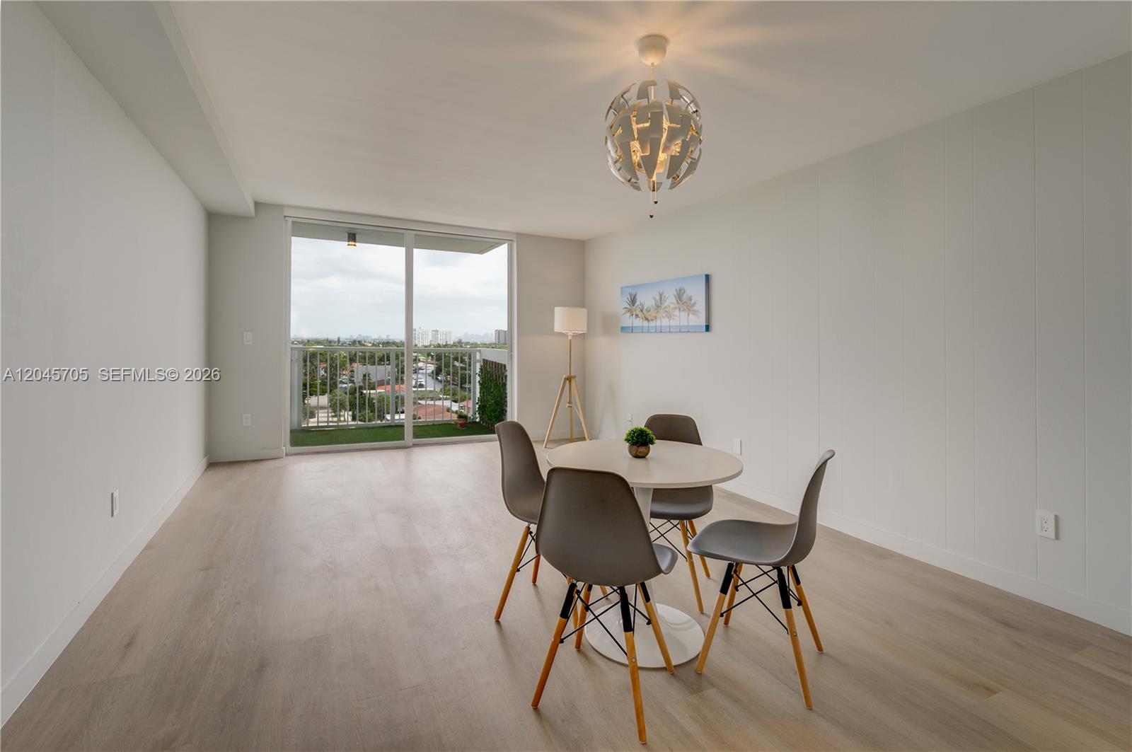 A dining area features a round table with four gray chairs and a balcony view — 2000 NE 135th St # 908, North Miami FL 33181, NORTH MIAMI, FL