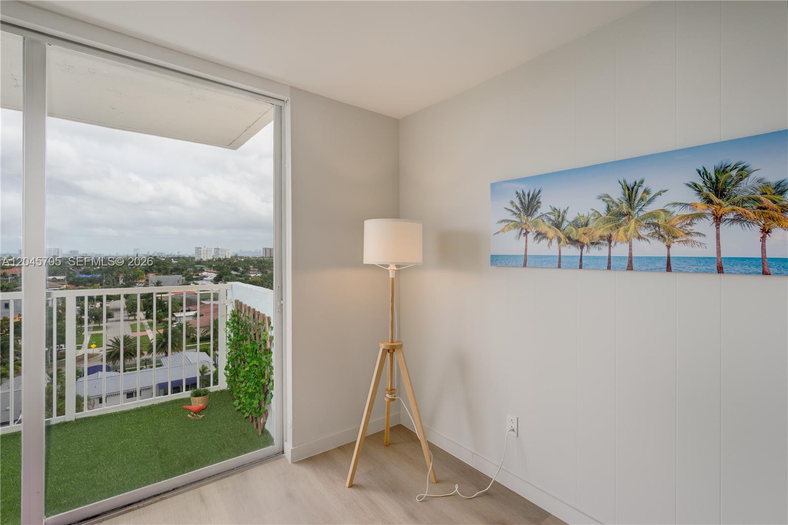 A room with a tripod floor lamp, a palm tree print, and a balcony view — 2000 NE 135th St # 908, North Miami FL 33181, NORTH MIAMI, FL