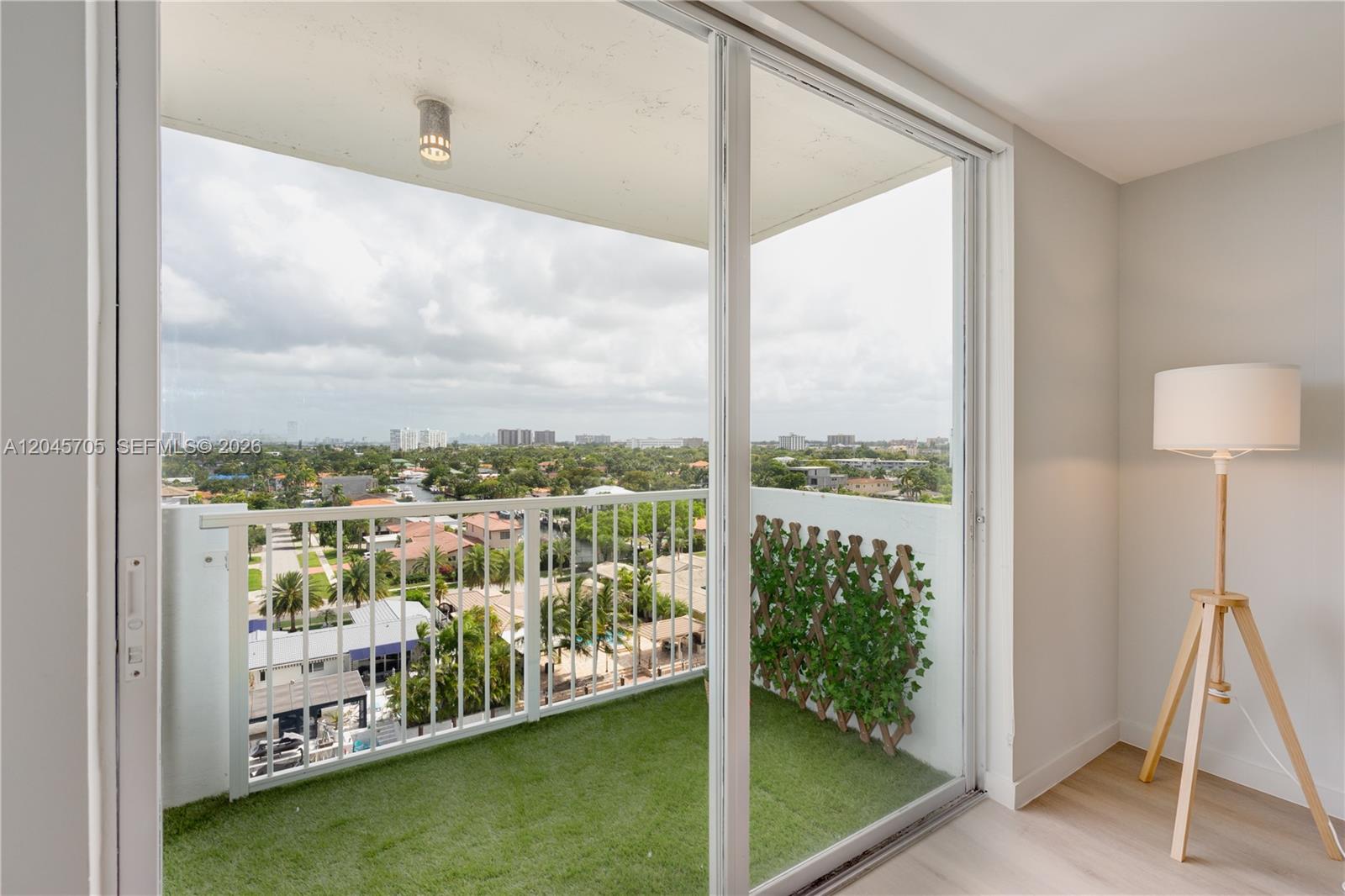 A balcony with artificial turf and a privacy screen overlooks a suburban neighborhood — 2000 NE 135th St # 908, North Miami FL 33181, NORTH MIAMI, FL