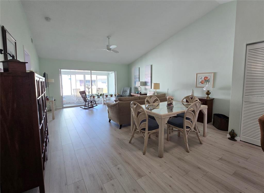 A living and dining area features light wood-look flooring, a glass-top table, and a sliding door — 6468 HAMLET DRIVE UNIT 4B, ENGLEWOOD, FL