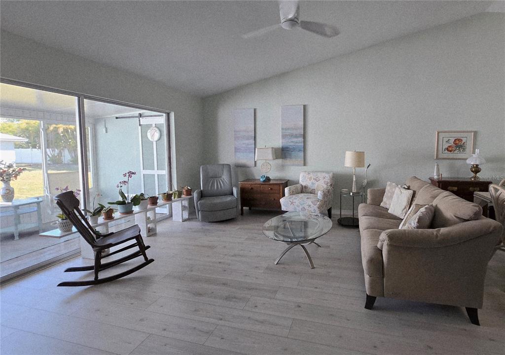 A living room features light wood-look flooring, a beige sofa, and a sliding glass door — 6468 HAMLET DRIVE UNIT 4B, ENGLEWOOD, FL