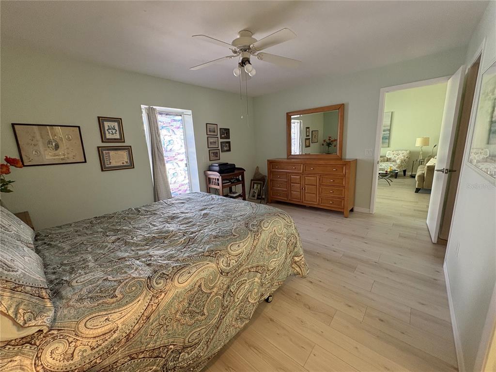 A bedroom with light green walls, wood-look flooring, a paisley bedspread, and a wooden dresser — 6468 HAMLET DRIVE UNIT 4B, ENGLEWOOD, FL