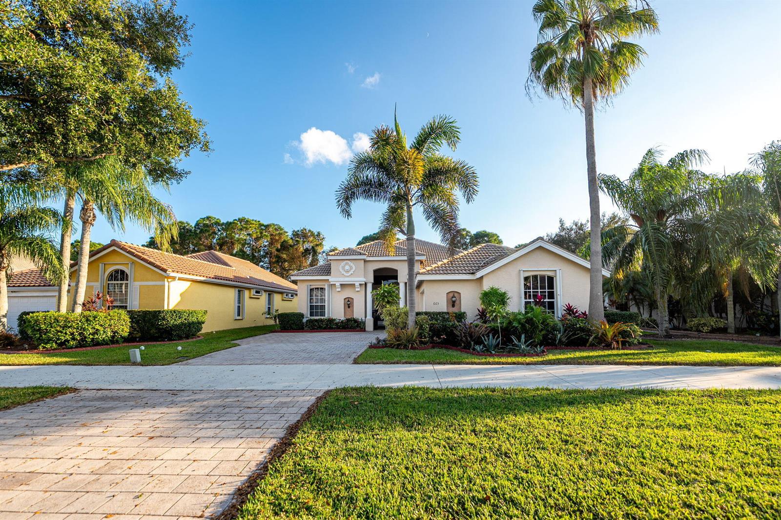 A single-story house with a paved driveway, palm trees, and a landscaped front yard — 665 SW Lake Charles Circle, FL 34986, FL