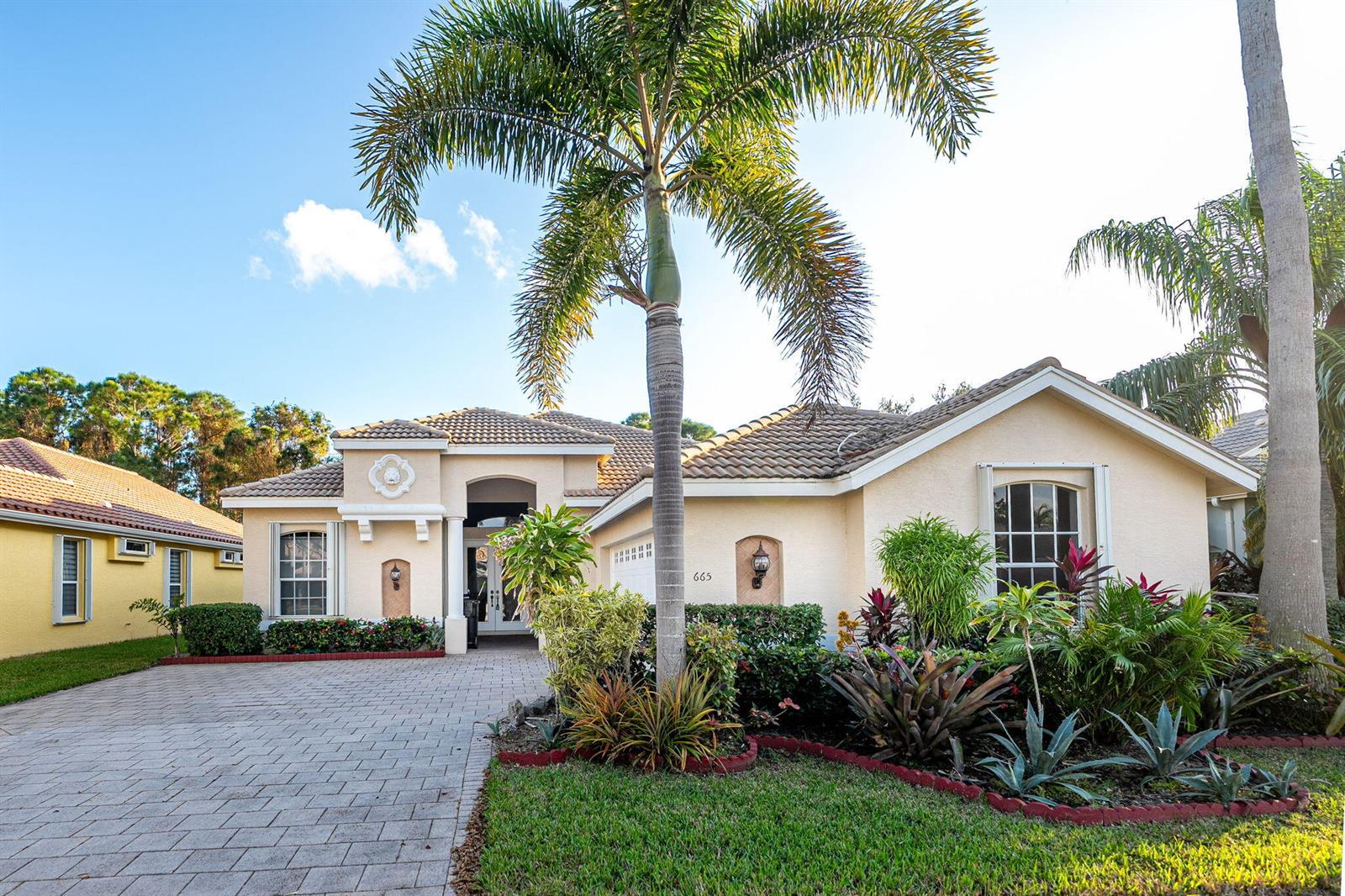 A single-story house with a paved driveway, palm trees, and a tiled roof — 665 SW Lake Charles Circle, FL 34986, FL
