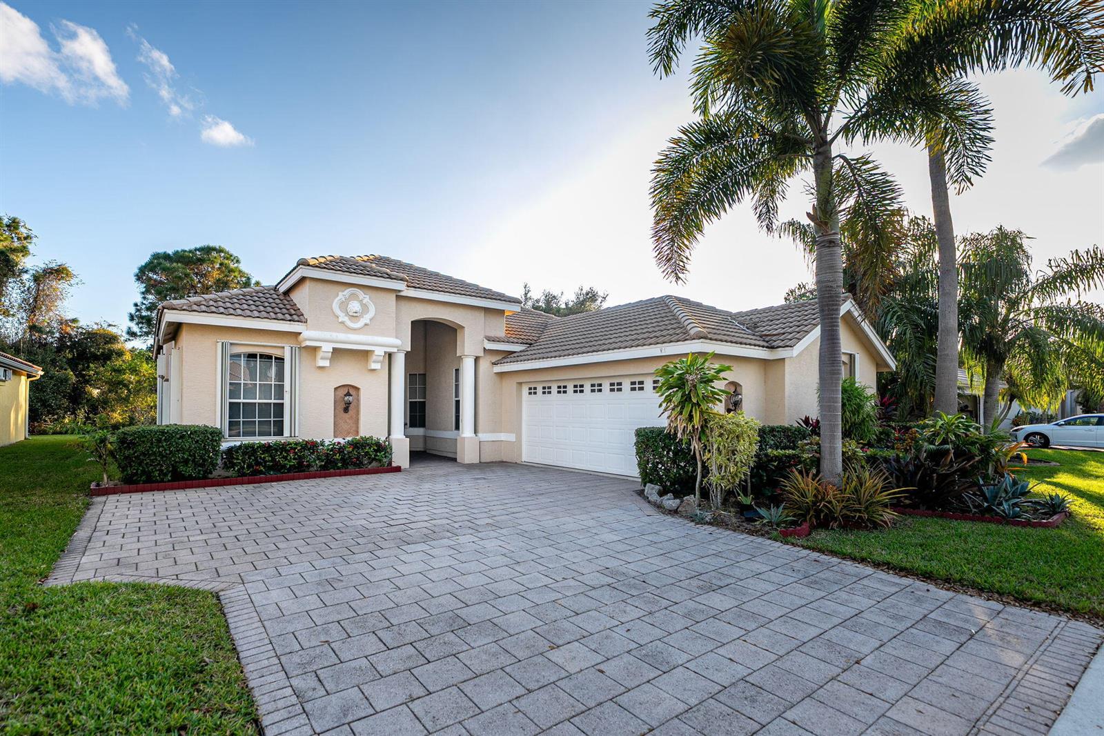 A single-story house with a tiled roof, beige stucco exterior, and a paved driveway — 665 SW Lake Charles Circle, FL 34986, FL