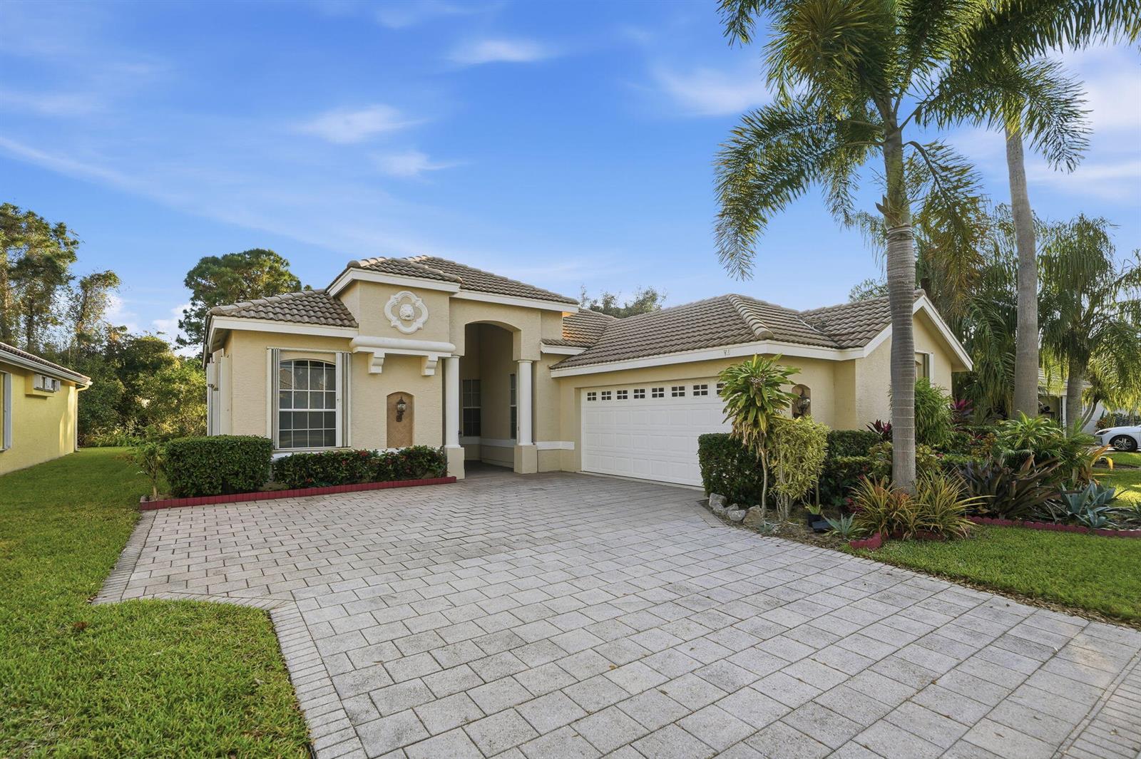 A single-story house with a beige stucco exterior, a tiled roof, and a paved driveway — 665 SW Lake Charles Circle, FL 34986, FL