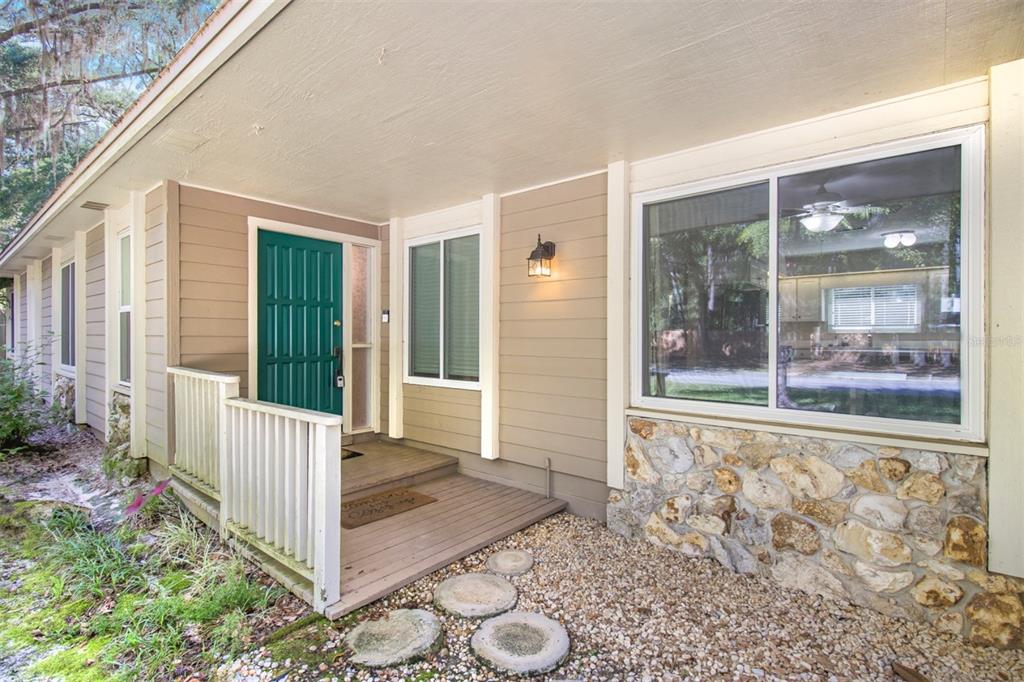 The exterior of a house features a green front door, tan siding, and stone accents — 2925 NW 31ST TERRACE, GAINESVILLE, FL