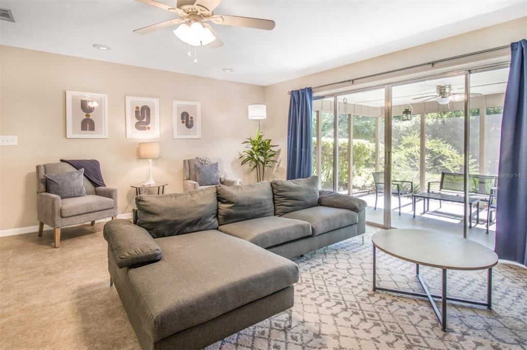A living room features a gray sectional sofa, an armchair, and a sliding glass door — 2925 NW 31ST TERRACE, GAINESVILLE, FL