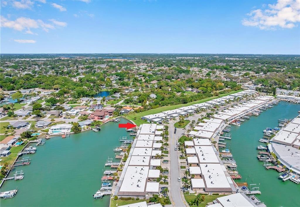 A wooden deck with patio furniture overlooks a canal with boat docks and houses — 403 BOCA CIEGA POINT BOULEVARD N, ST PETERSBURG, FL