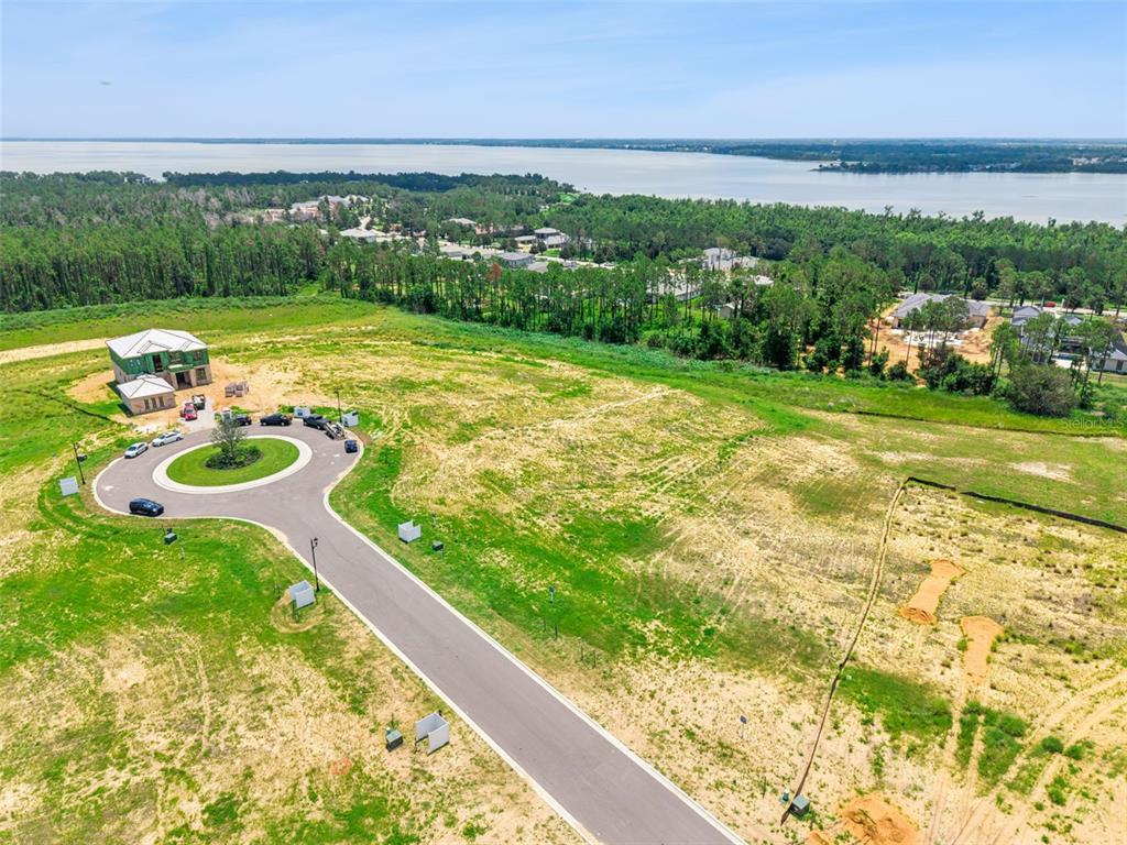 An aerial view shows a cul-de-sac with a house under construction near a large lake — 15454 APENNINE WAY, MONTVERDE, FL