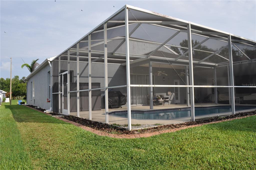 A backyard swimming pool enclosed by a screened lanai attached to the side of a house — 1842 RIDGELAKE COURT, WESLEY CHAPEL, FL