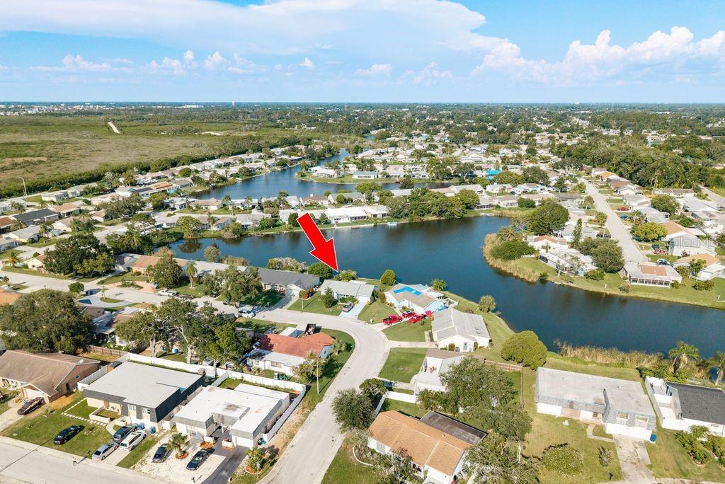 An aerial view of a residential neighborhood featuring a house marked with a red arrow — 3552 BLUEBELL LANE, HOLIDAY, FL
