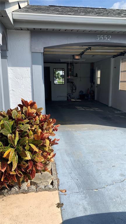 A view of a covered carport with a concrete floor and a nearby potted plant — 3552 BLUEBELL LANE, HOLIDAY, FL