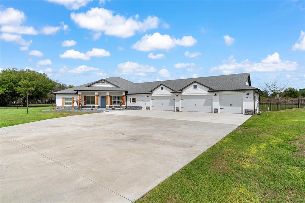 A single-story house with a large concrete driveway and a three-car garage — 4821 SUNNYSIDE DRIVE, FRUITLAND PARK, FL