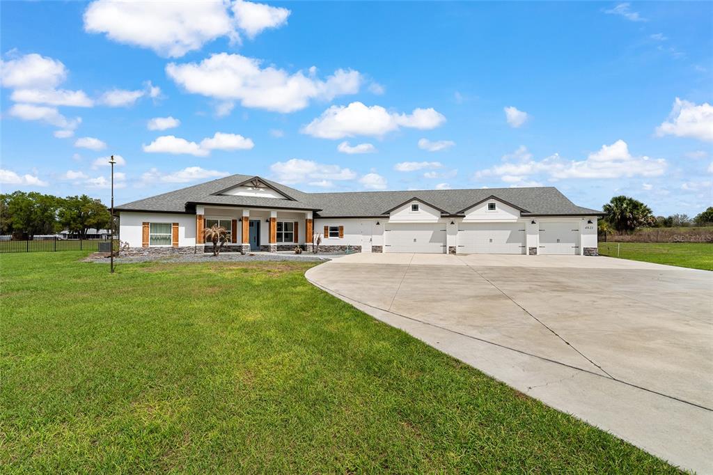 A single-story house with a white exterior, stone accents, and a three-car garage — 4821 SUNNYSIDE DRIVE, FRUITLAND PARK, FL