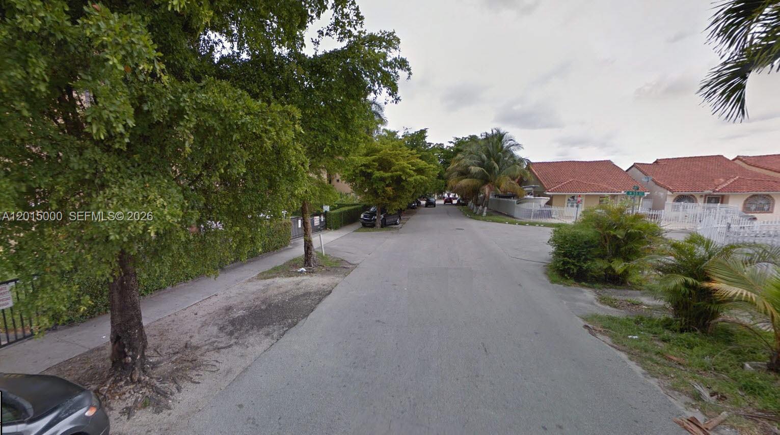 A residential street lined with trees, parked cars, and single-story houses with red tile roofs — 5490 W 21st Ct # 313, Hialeah FL 33016, HIALEAH, FL