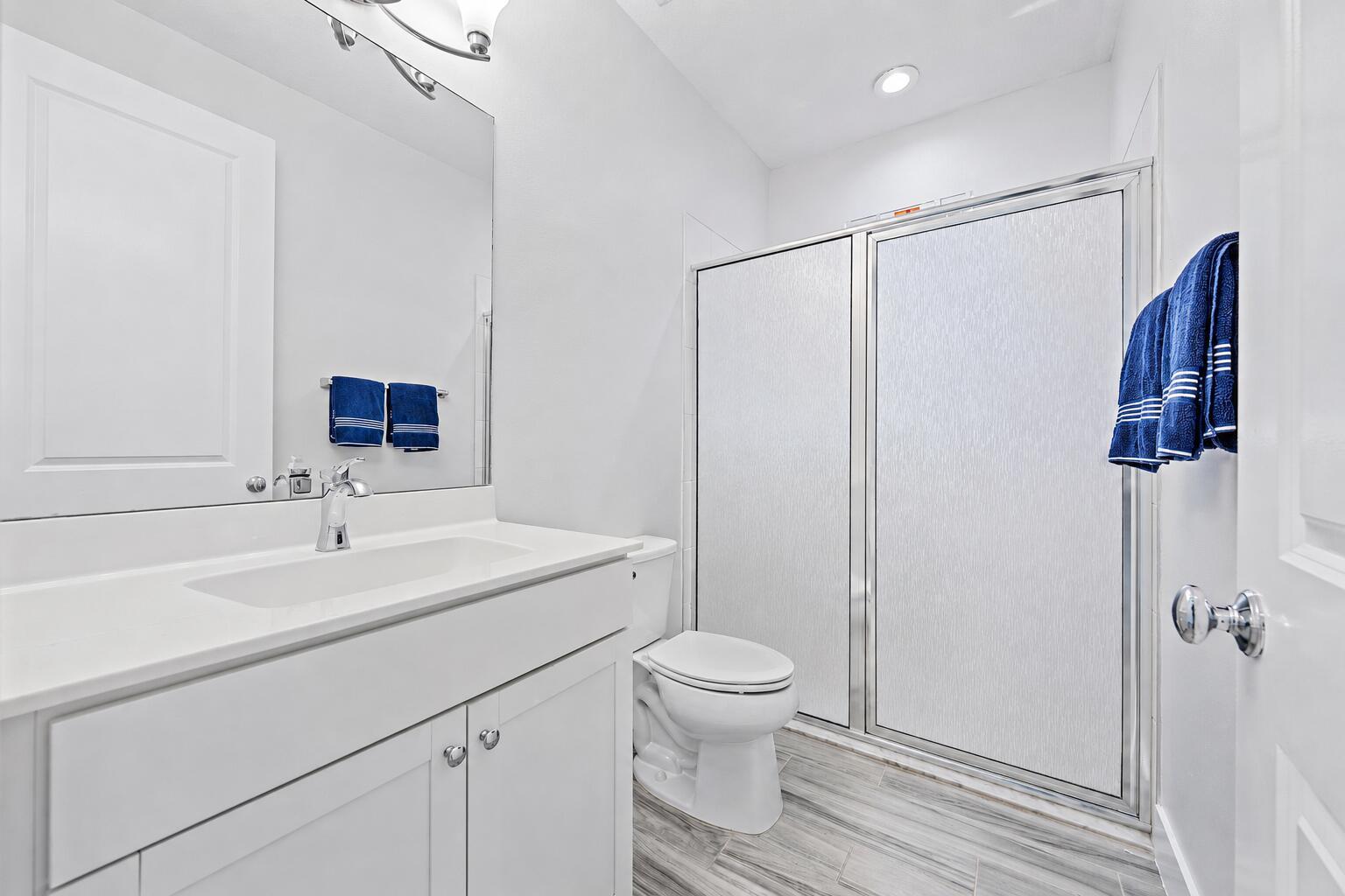 A bathroom features a white vanity, a toilet, and a walk-in shower with sliding doors — 4145 Faraday Way, Palm Beach Gardens FL 33418, PALM BEACH GARDENS, FL