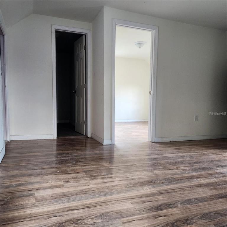 An interior view shows a room with wood-look flooring and two open doorways — 1414 MINNESOTA AVENUE UNIT B, ST CLOUD, FL