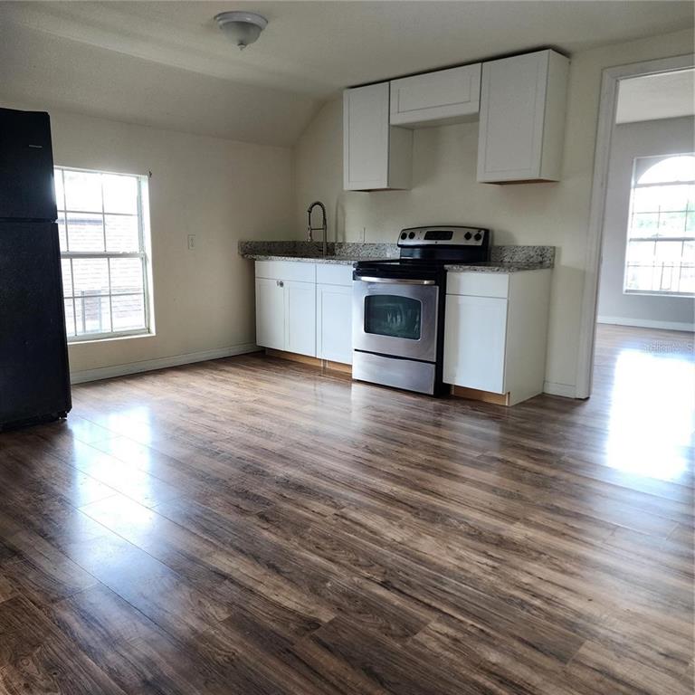 A kitchen features white cabinets, granite countertops, stainless steel appliances, and wood-look flooring — 1414 MINNESOTA AVENUE UNIT B, ST CLOUD, FL