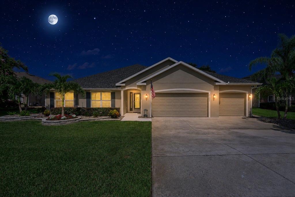 A single-story house with a two-car garage and a landscaped front yard at night — 11332 LITTLE NELLIE DRIVE, CLERMONT, FL
