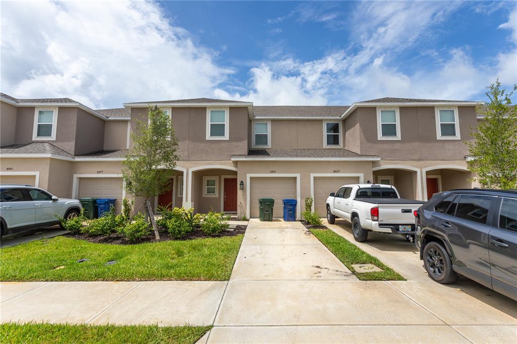 A row of two-story townhomes with attached garages and driveways under a cloudy sky — 8473 LUNAR SKYE STREET, SARASOTA, FL