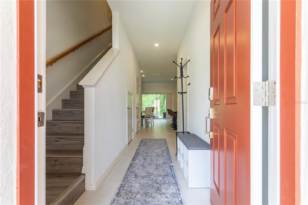 An entryway features a staircase, a long runner rug, and a view toward a dining area — 8473 LUNAR SKYE STREET, SARASOTA, FL