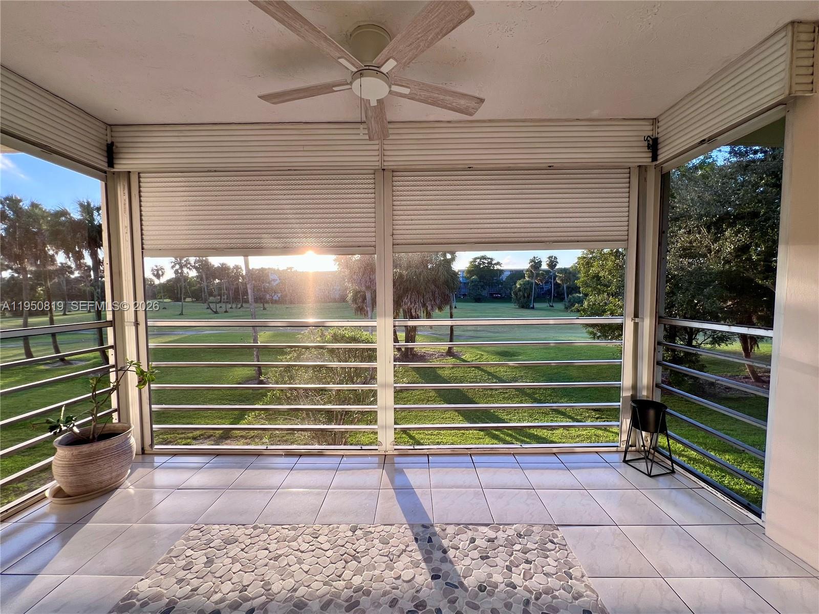A tiled balcony features a ceiling fan, roll-down shutters, and views of a golf course — 907 Cypress Ter # 203, Pompano Beach FL 33069, POMPANO BEACH, FL