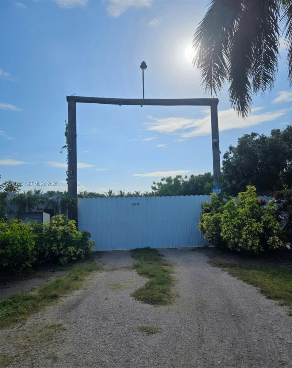 A gravel driveway leads to a gated entrance framed by two wooden posts — 19550 SW 162nd Ave, Miami FL 33187, MIAMI, FL