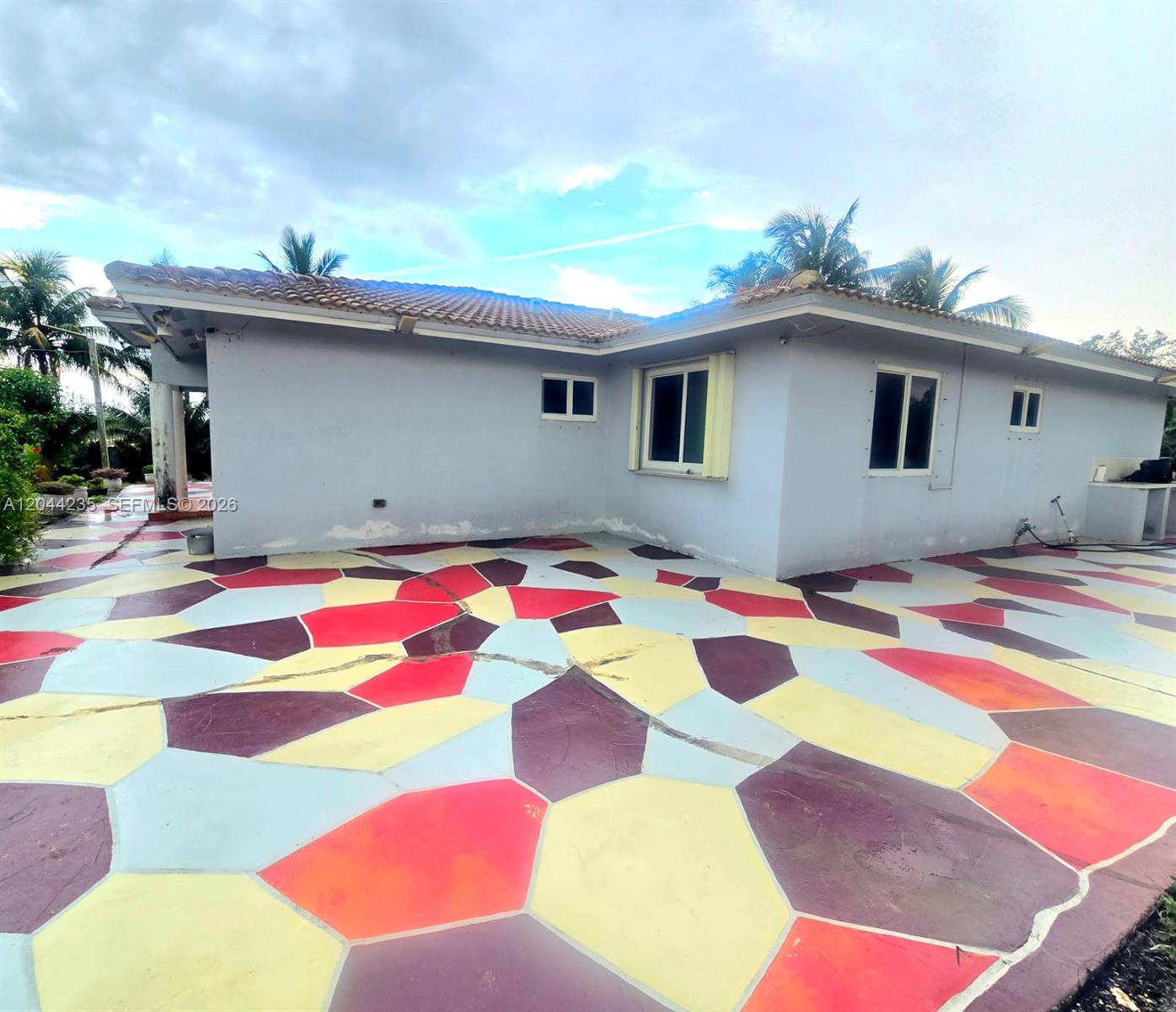 The exterior of a house features a multi-colored, geometric-patterned concrete patio — 19550 SW 162nd Ave, Miami FL 33187, MIAMI, FL