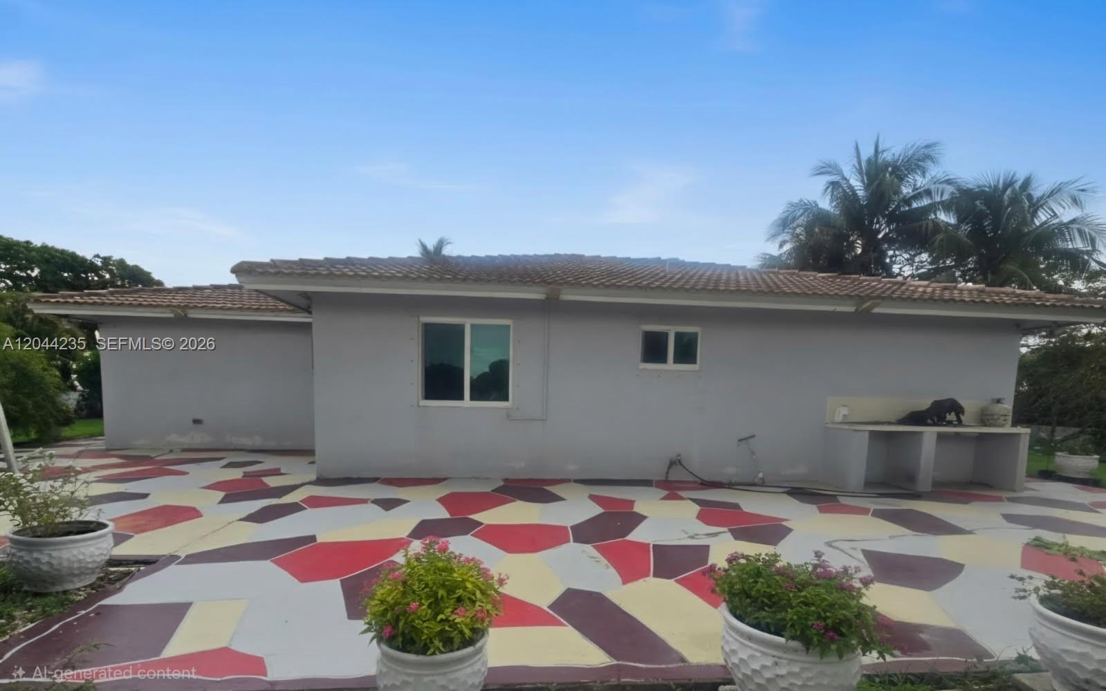 The exterior of a house features a multi-colored geometric patio and a concrete outdoor counter — 19550 SW 162nd Ave, Miami FL 33187, MIAMI, FL