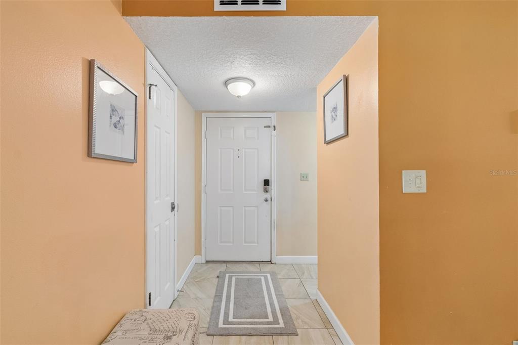 An entryway features peach-colored walls, a white front door, and light-colored tile flooring — 6085 BAHIA DEL MAR BOULEVARD UNIT 106, ST PETERSBURG, FL