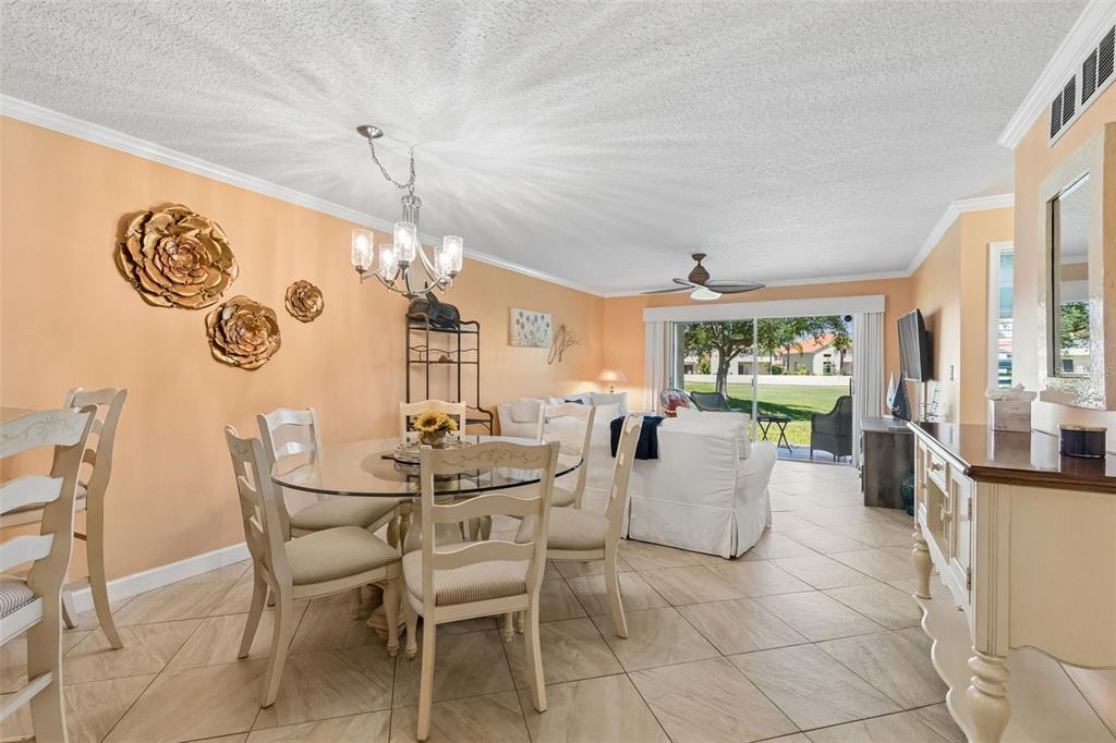 A dining area and living room with tile floors, peach walls, and a glass table — 6085 BAHIA DEL MAR BOULEVARD UNIT 106, ST PETERSBURG, FL