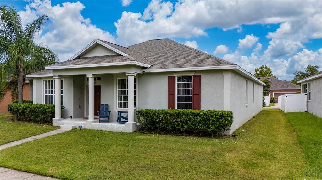 A single-story house with a covered front porch, tan stucco siding, and red window shutters — 3108 WESTBROOK ROAD, KISSIMMEE, FL