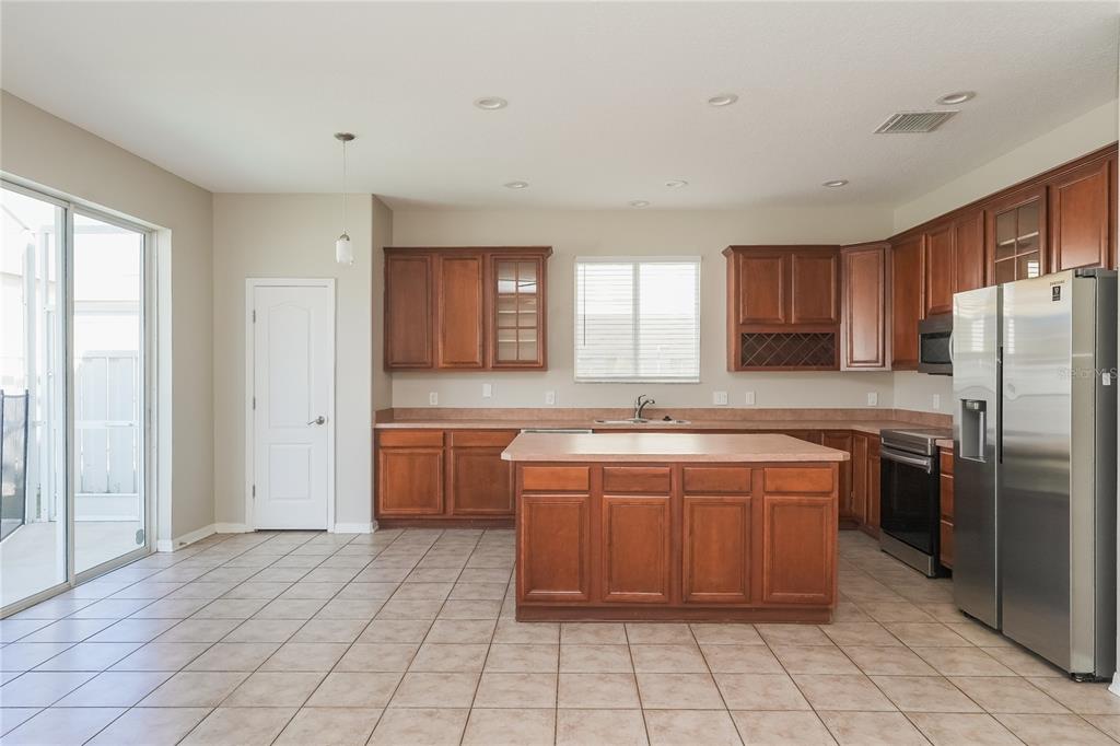 A kitchen with wood cabinets, a central island, stainless steel appliances, and tile flooring — 12125 FOX BLOOM AVENUE, GIBSONTON, FL