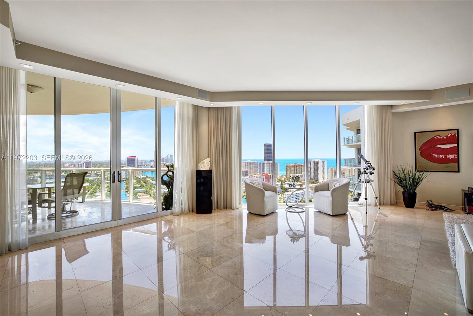 A bright living room features floor-to-ceiling windows, marble tile flooring, and a balcony view — 21200 Point Pl, Aventura FL 33180, AVENTURA, FL