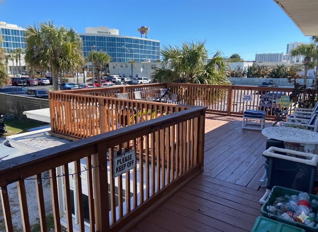 A wooden deck with railings overlooks a parking lot and a large hotel building — 938 N GRANDVIEW AVENUE, DAYTONA BEACH, FL