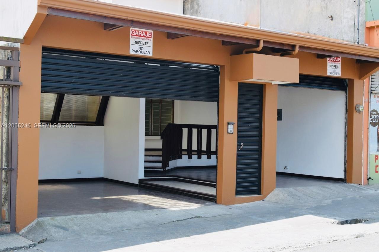 A street-level view shows two open garage bays with metal roll-up doors and signage — Cartago Cartago, FL, FL