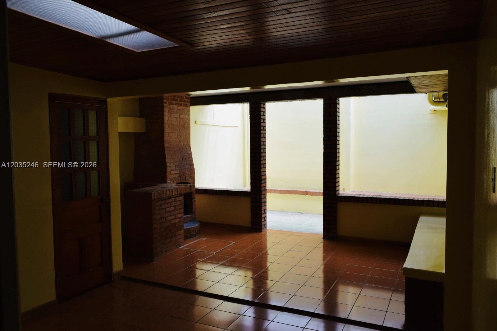 An indoor patio features a brick fireplace, tiled floors, and a wood-paneled ceiling — Cartago Cartago, FL, FL