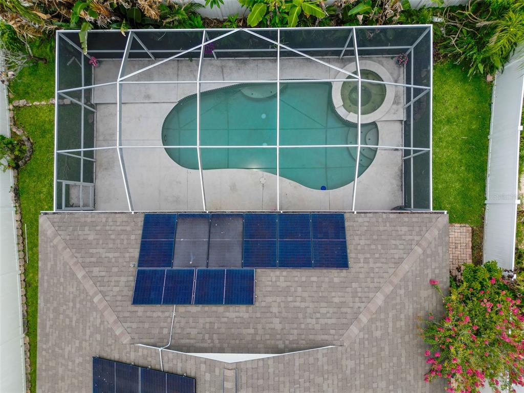 An aerial view shows a house roof with solar panels and a screened-in swimming pool — 2003 BERRY LAKE DRIVE, BRANDON, FL